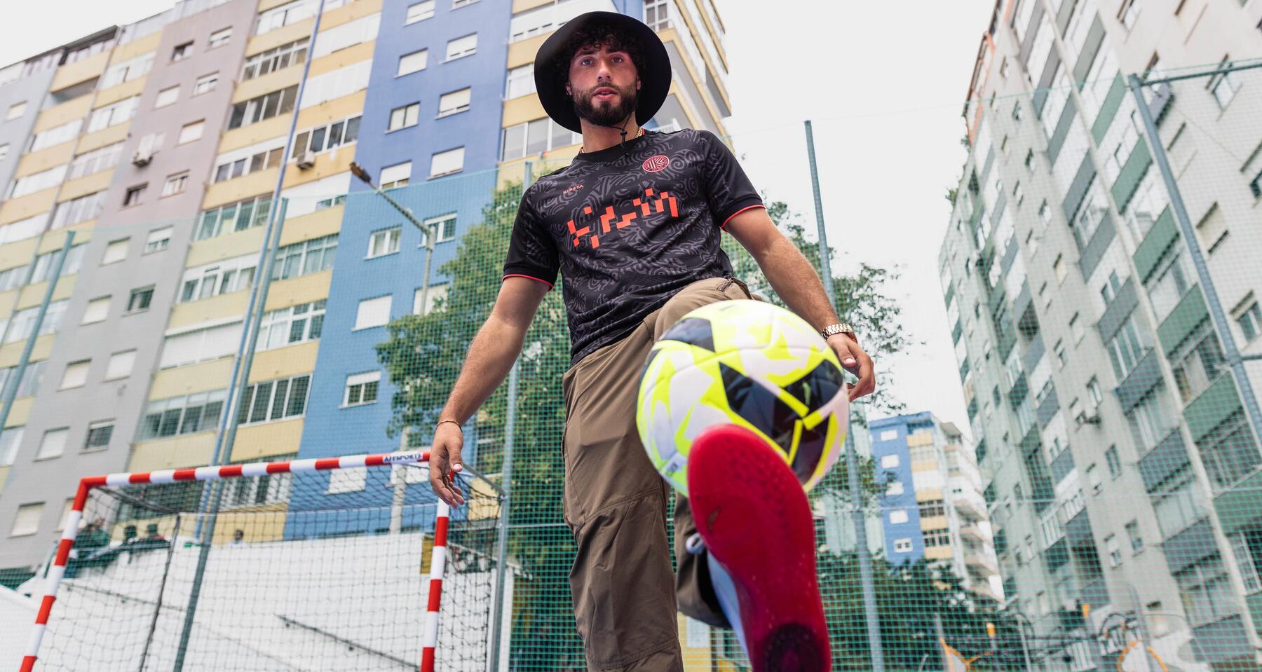 Man kicking football up in urban area