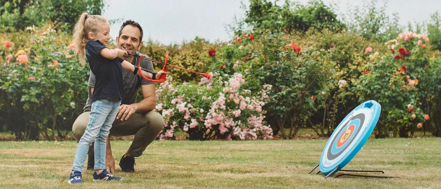 Father teaching daughter how to do archery
