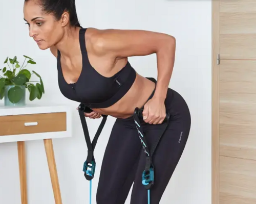 Kobieta w stroju sportowym ćwicząca martwy ciąg z gumą