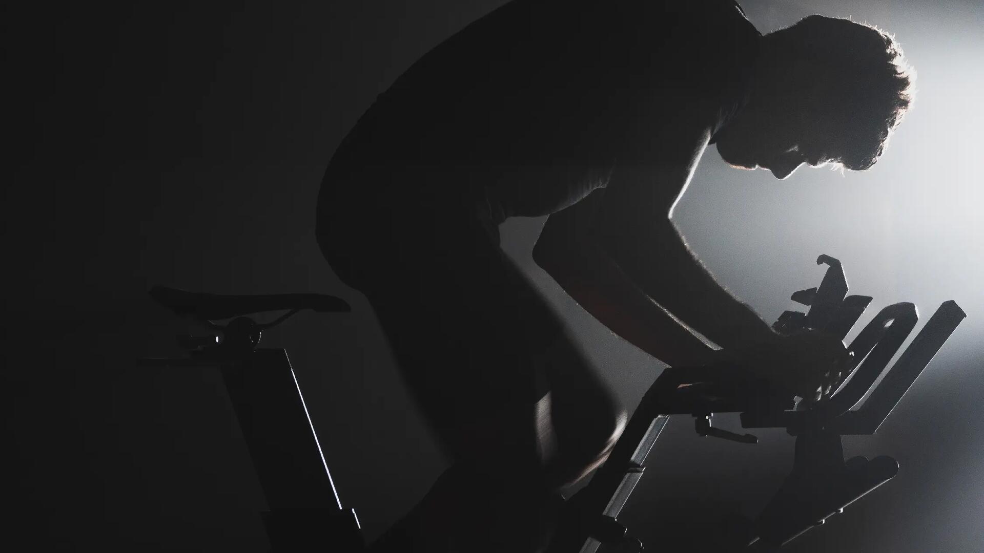 mężczyzna w odzieży sportowej na rowerku stanjonarnym