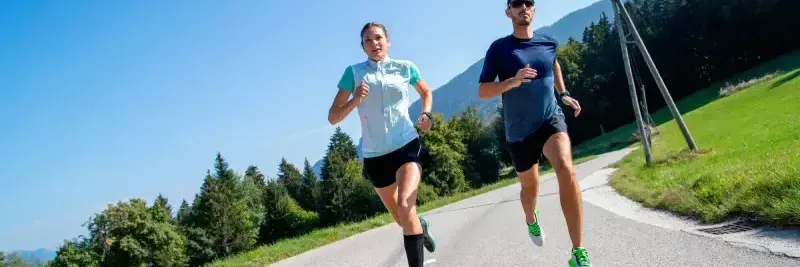 Ludzie w odzieży sportowej biegający po drodze asfaltowej