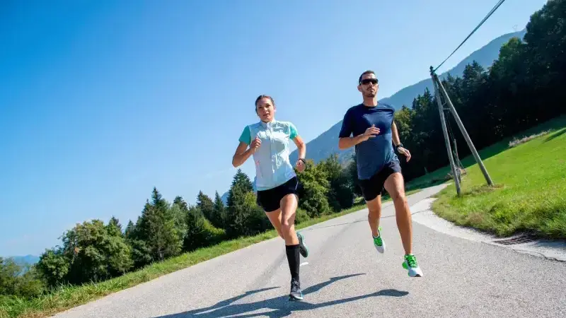 Kobieta i mężczyzna w odzieży sportowej biegający po asfalcie