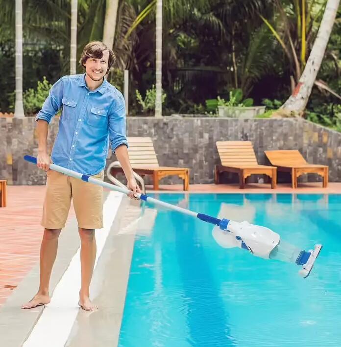 homem a limpar a piscina com aspirador