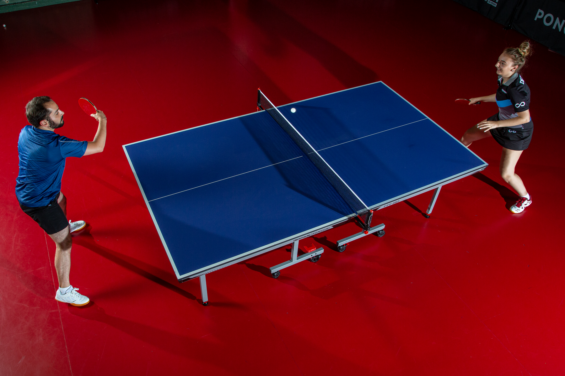 man and woman playing table tennis indoors