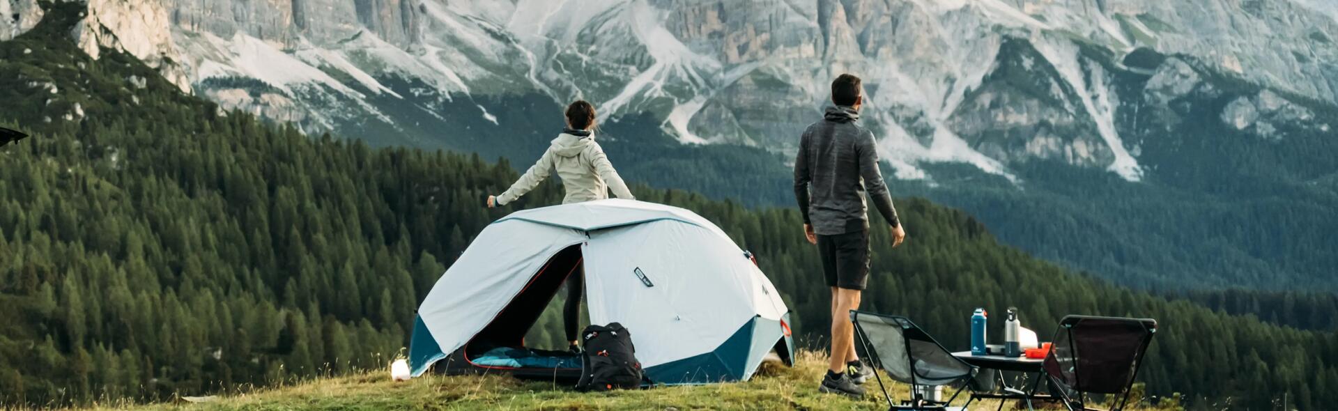 kobieta i mężczyzna stojący przed namiotem turystycznym w górach